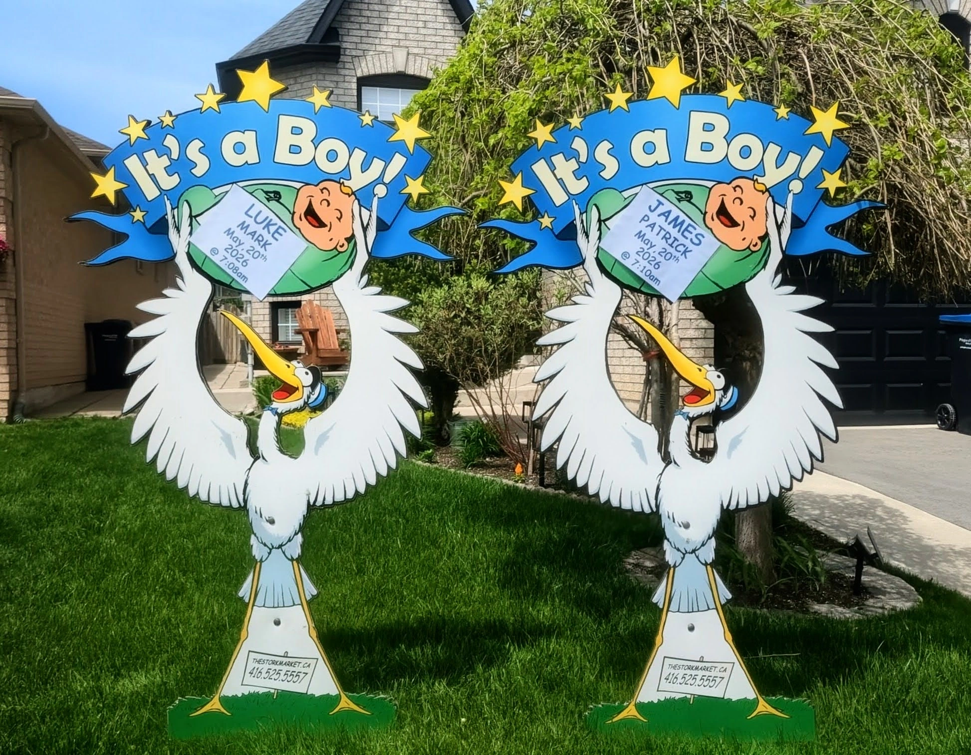 Twin blue It’s a Boy lawn stork signs for Luke Mark and James Patrick side by side on a green lawn — The Stork Market, serving Brampton and the GTA