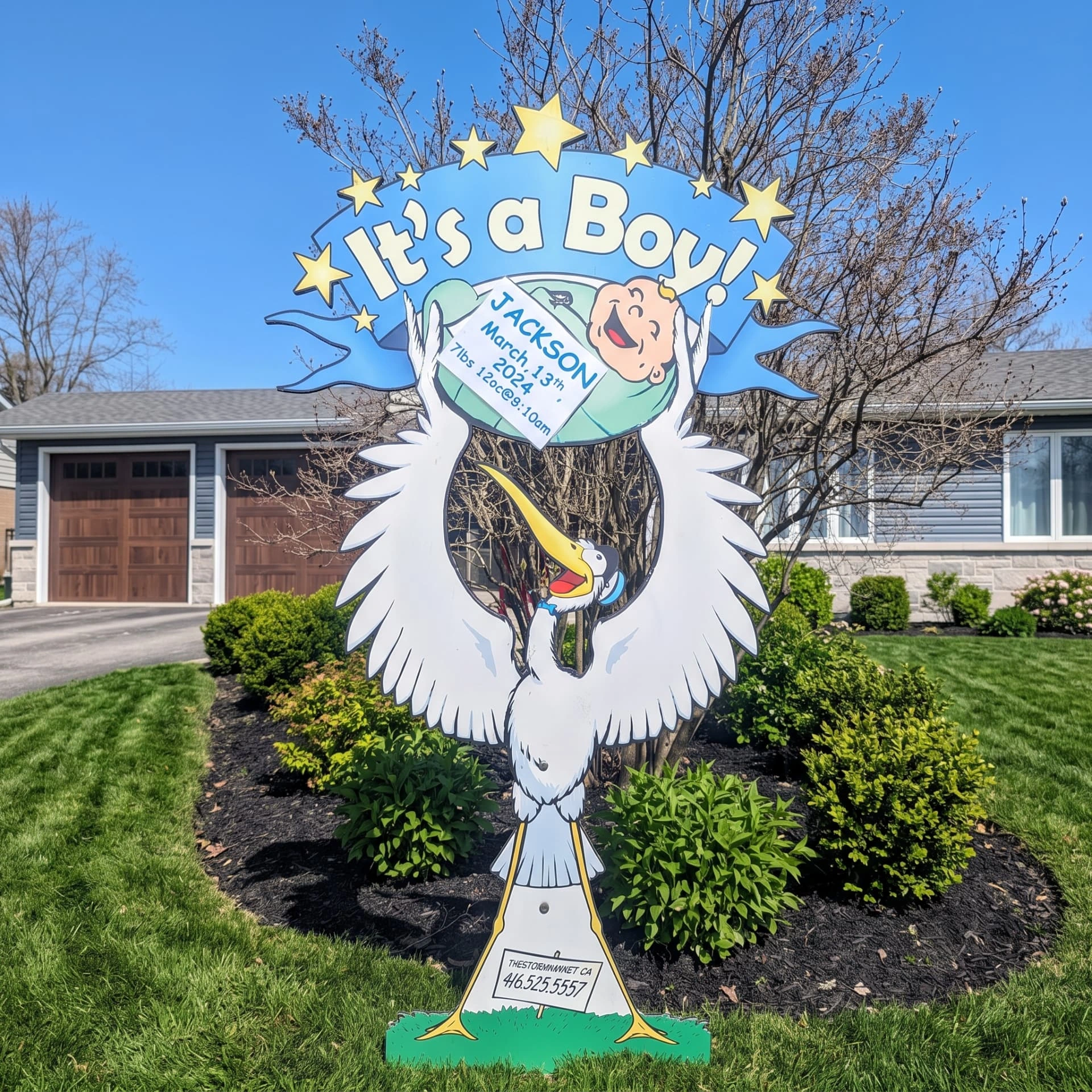 Blue It’s a Boy lawn stork sign personalized for Jackson on a landscaped front lawn — The Stork Market, serving Brampton and the GTA