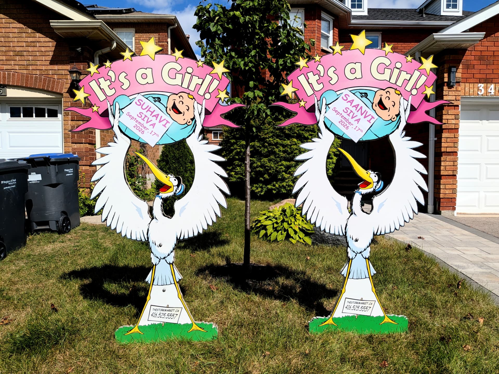 Twin pink Suhavi Siva and Saanvi Siva lawn stork signs with yellow stars by a brick home — The Stork Market, serving Brampton and the GTA